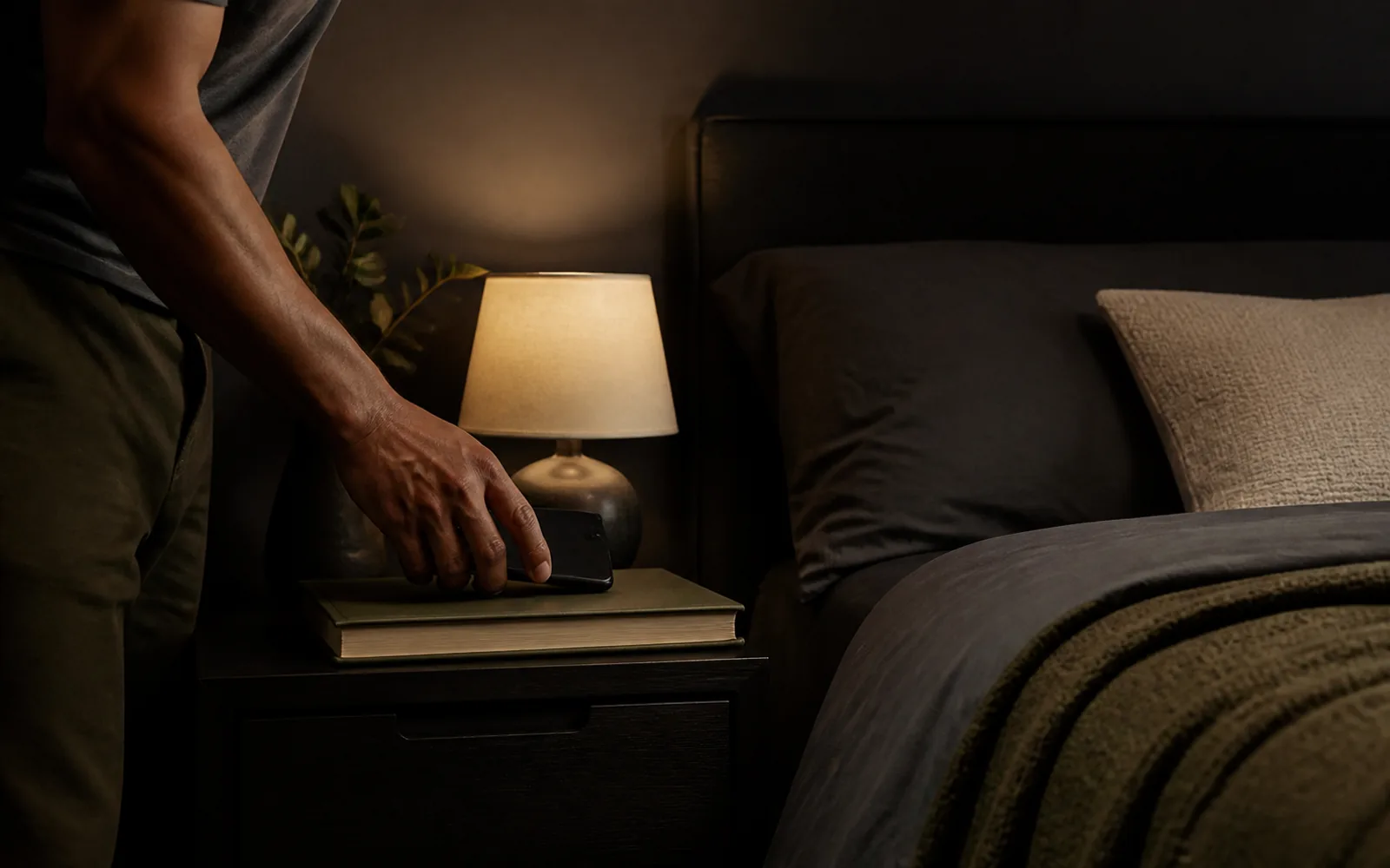 Adulte préparant une routine du soir apaisée dans une chambre aux lumières douces.