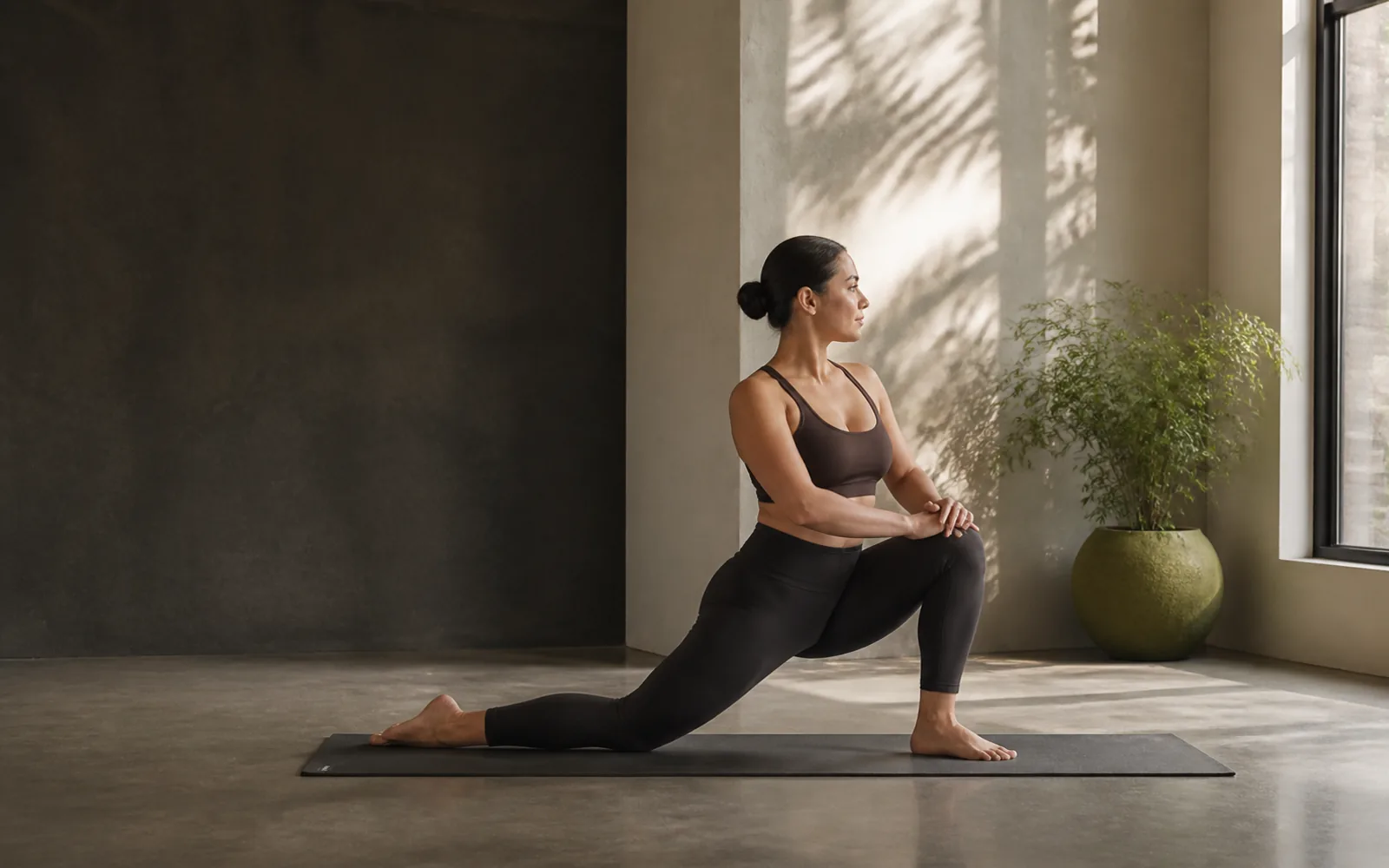 Pratiquante de yoga en posture debout stable dans un studio simple et lumineux.